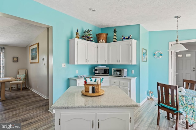 30 Turtle Dove Dr, Rehoboth Beach, DE 19971 - kitchen featuring a textured ceiling, stainless steel microwave, wood finished floors, baseboards, and white cabinets