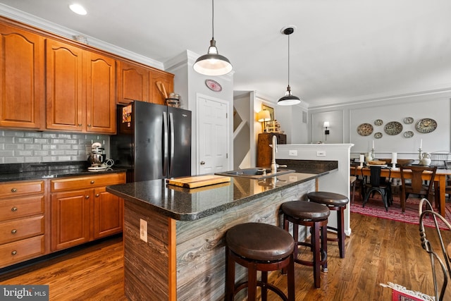 43614 Dunhill Cup Sq, Ashburn, VA 20147 - kitchen with freestanding refrigerator, a sink, a breakfast bar area, a kitchen island with sink, and brown cabinets