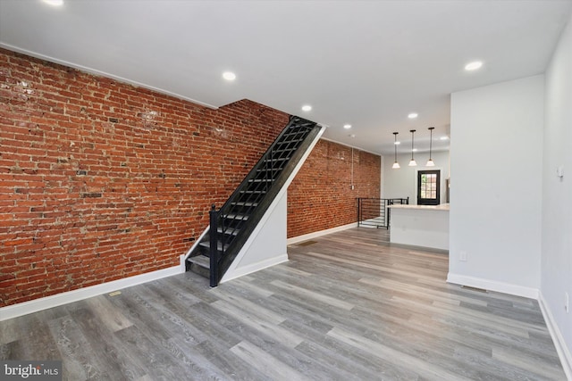 233 S Frazier St, Philadelphia, PA 19139 - unfurnished living room with brick wall, baseboards, wood finished floors, and recessed lighting