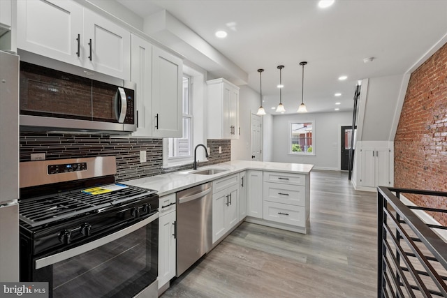 233 S Frazier St, Philadelphia, PA 19139 - kitchen featuring stainless steel appliances, a sink, a peninsula, white cabinets, and light wood-style floors