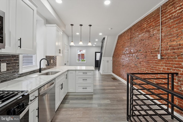 233 S Frazier St, Philadelphia, PA 19139 - kitchen with stainless steel appliances, a sink, a peninsula, light stone countertops, and brick wall