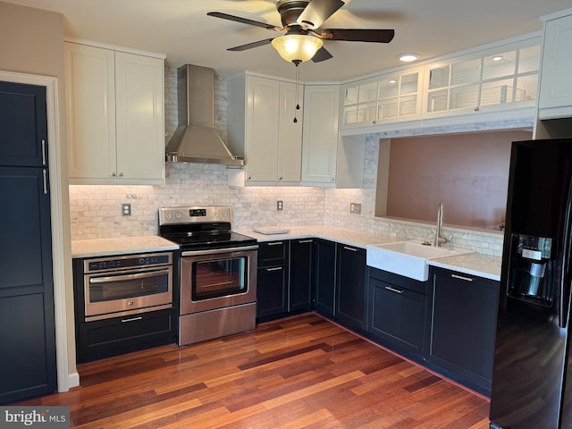 3942 Forest Valley Rd, Baltimore, MD 21234 - kitchen featuring stainless steel appliances, wall chimney range hood, white cabinets, a ceiling fan, and backsplash