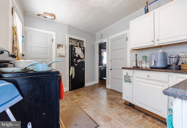 28 Chestnut St, Salem, NJ 08079 - kitchen with freestanding refrigerator, dark countertops, white cabinetry, and stone finish floors