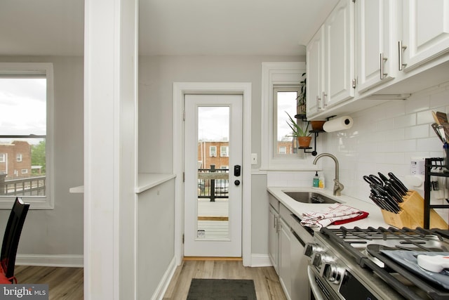 1702 Lang Pl NE, Washington, DC 20002 - kitchen featuring a sink, tasteful backsplash, light wood-type flooring, white cabinets, and healthy amount of natural light