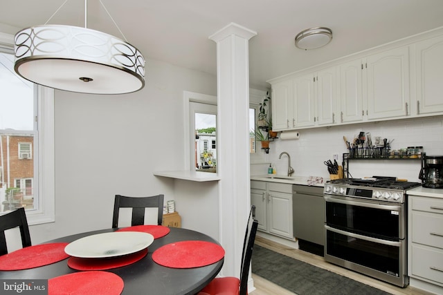 1702 Lang Pl NE, Washington, DC 20002 - kitchen with appliances with stainless steel finishes, a sink, white cabinetry, decorative columns, and decorative backsplash