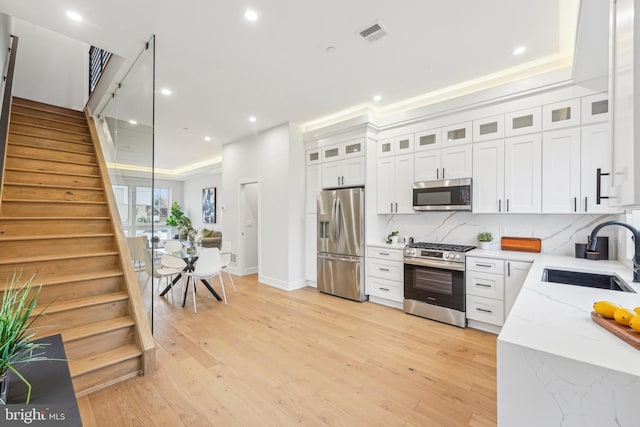 3005 Gaul St, Philadelphia, PA 19134 - kitchen featuring stainless steel appliances, a sink, light stone countertops, decorative backsplash, and light wood-type flooring