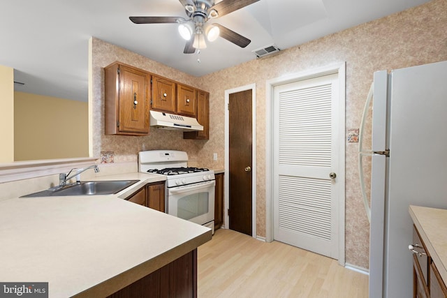 127 Mohican Ln, Little Egg Harbor Twp, NJ 08087 - kitchen featuring white appliances, a sink, under cabinet range hood, light wood-style flooring, and light countertops