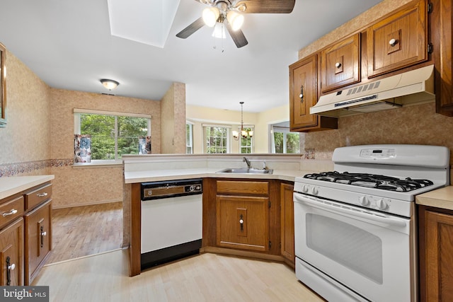 127 Mohican Ln, Little Egg Harbor Twp, NJ 08087 - kitchen with white appliances, under cabinet range hood, a sink, brown cabinetry, and light wood finished floors