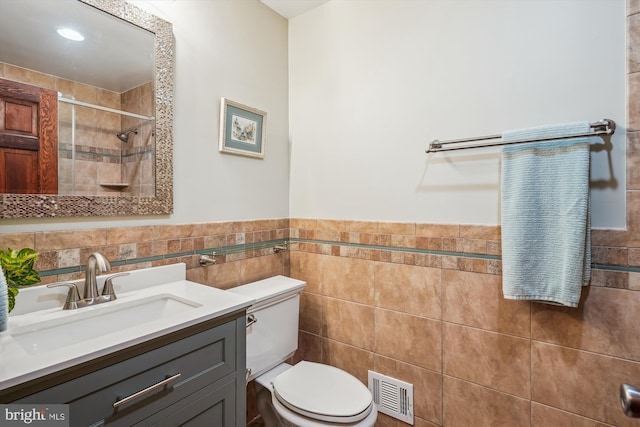 4499 Larchmont Ct, Dumfries, VA 22025 - bathroom featuring a tile shower, toilet, tile walls, vanity, and a wainscoted wall