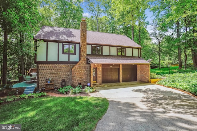 4499 Larchmont Ct, Dumfries, VA 22025 - tudor-style house featuring brick siding, a shingled roof, driveway, a chimney, and an attached garage