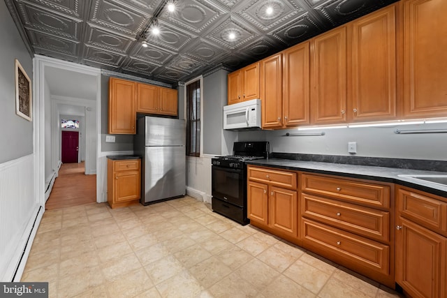812 Powers St, Baltimore, MD 21211 - kitchen with freestanding refrigerator, white microwave, black range with gas cooktop, dark countertops, and a baseboard radiator