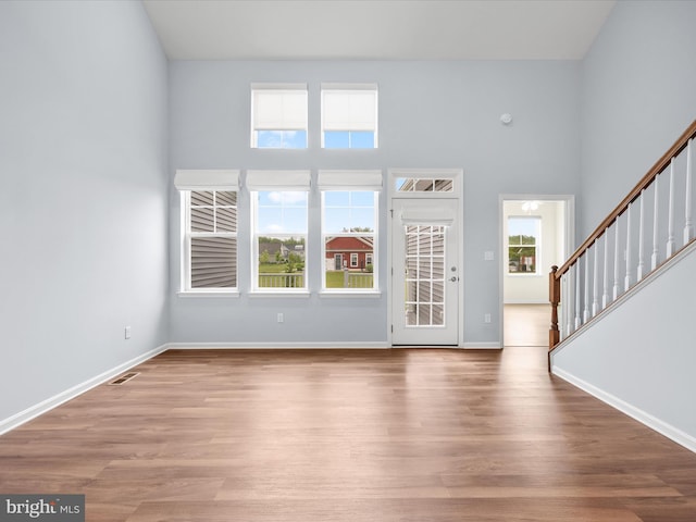 306 Prospect St, Milton, DE 19968 - unfurnished living room featuring stairs, wood finished floors, baseboards, and a high ceiling