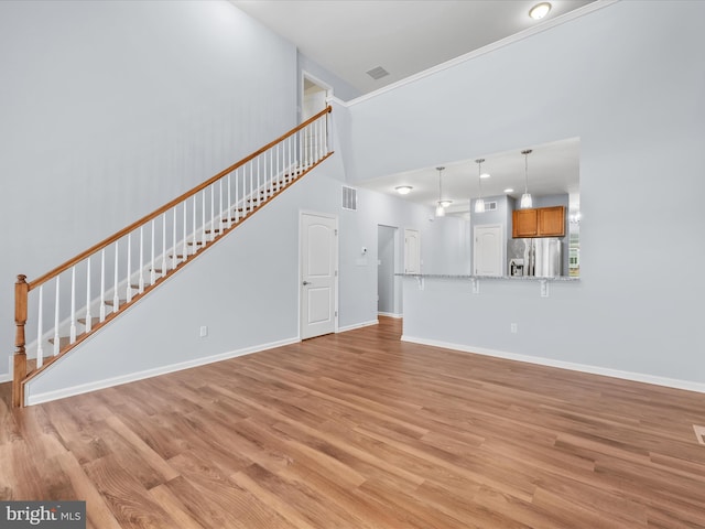 306 Prospect St, Milton, DE 19968 - unfurnished living room featuring stairway, light wood-style floors, baseboards, and a towering ceiling