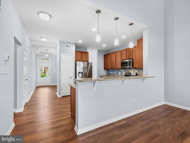306 Prospect St, Milton, DE 19968 - kitchen featuring appliances with stainless steel finishes, a peninsula, brown cabinets, a kitchen bar, and dark wood-style floors