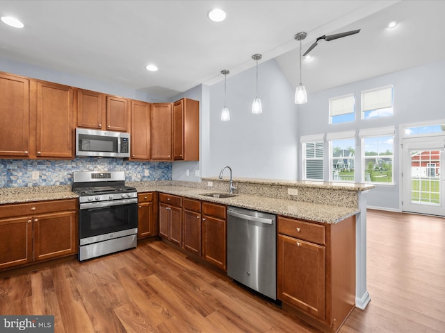 306 Prospect St, Milton, DE 19968 - kitchen with stainless steel appliances, a sink, a peninsula, brown cabinets, and recessed lighting