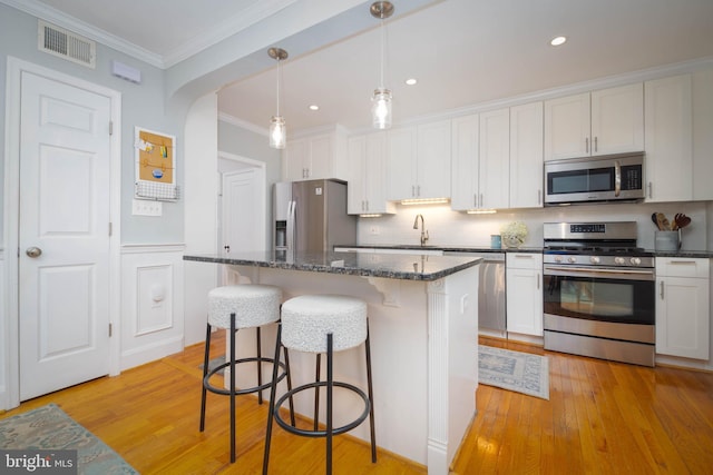 409 Regester Ave, Baltimore, MD 21212 - kitchen with appliances with stainless steel finishes, a breakfast bar area, light wood finished floors, a kitchen island, and decorative backsplash