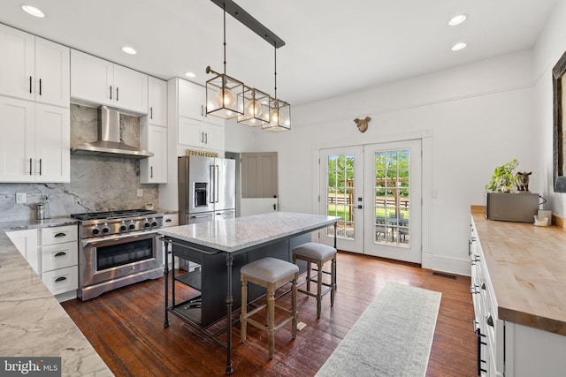 23350 Cedar Mountain Dr, Rapidan, VA 22733 - kitchen featuring wall chimney range hood, premium appliances, tasteful backsplash, a breakfast bar, and white cabinetry