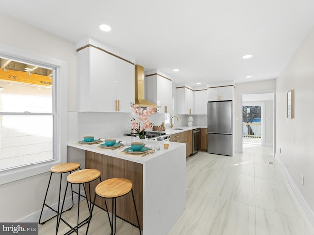 212 W 13th Ave, Wildwood, NJ 08260 - kitchen featuring appliances with stainless steel finishes, wall chimney range hood, a sink, a peninsula, and light countertops