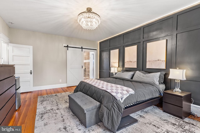 225 Wayne Ave, Lansdowne, PA 19050 - bedroom featuring a chandelier, a barn door, wood finished floors, and baseboards