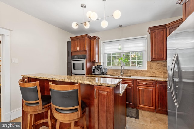 225 Wayne Ave, Lansdowne, PA 19050 - kitchen with stainless steel appliances, a sink, tasteful backsplash, decorative light fixtures, and light stone counters