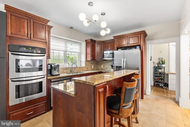 225 Wayne Ave, Lansdowne, PA 19050 - kitchen featuring appliances with stainless steel finishes, a sink, light stone counters, backsplash, and a center island