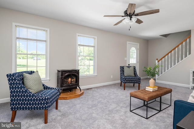 11307 Urieville Ln, Worton, MD 21678 - living area featuring a wood stove, baseboards, ceiling fan, stairs, and carpet