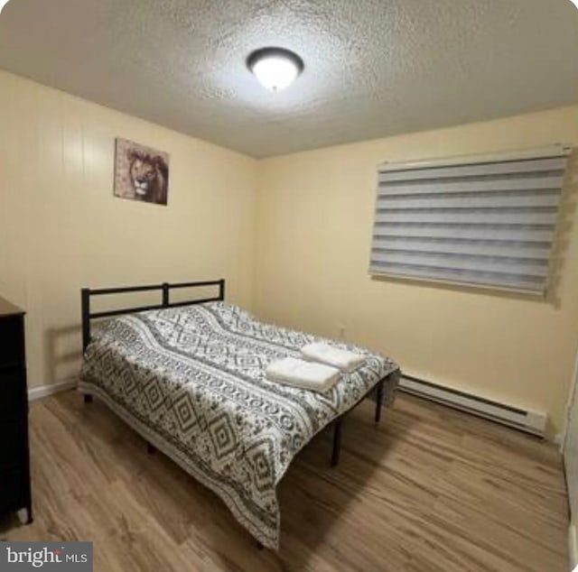 7108 Robinwood Dr, Tobyhanna, PA 18466 - bedroom with baseboard heating, a textured ceiling, wood finished floors, and baseboards