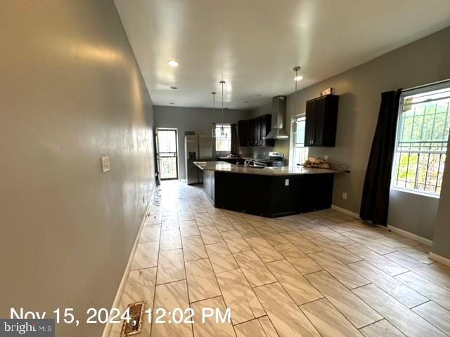 2468 Greenmount Ave, Baltimore, MD 21218 - kitchen with wall chimney range hood, stainless steel appliances, baseboards, a peninsula, and dark cabinetry