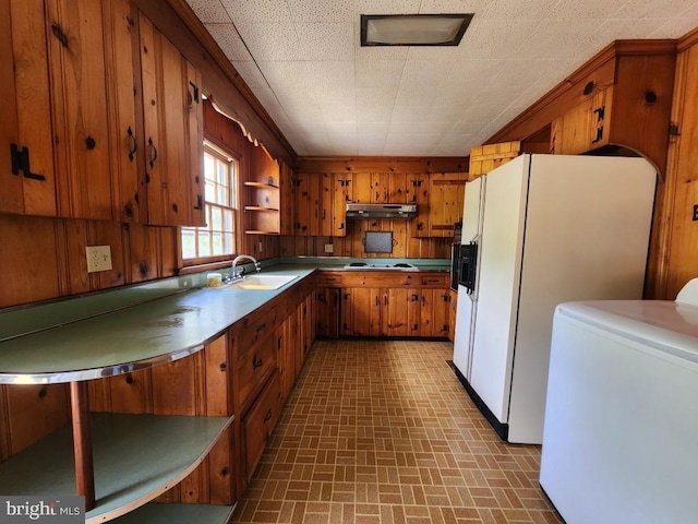 6428 Quantico Rd, Quantico, MD 21856 - kitchen featuring under cabinet range hood, washer / clothes dryer, brown cabinets, brick patterned floors, and a sink