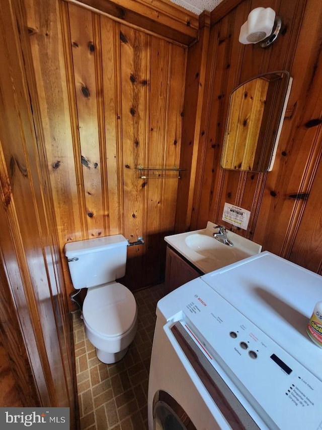 6428 Quantico Rd, Quantico, MD 21856 - bathroom featuring washer / dryer, toilet, wooden walls, and a sink