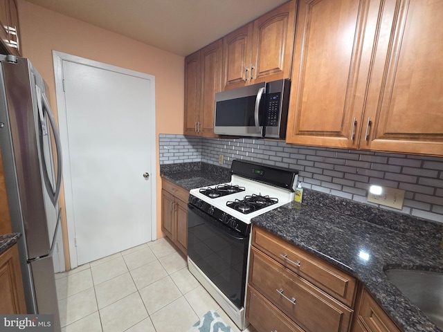 2704 Adams Ct, North Wales, PA 19454 - kitchen with stainless steel appliances, brown cabinets, backsplash, dark stone counters, and light tile patterned floors