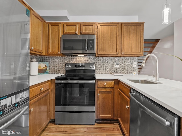 1806 Bryant St NE Unit 1806, Washington, DC 20018 - kitchen with appliances with stainless steel finishes, a sink, light countertops, brown cabinetry, and light wood-style flooring