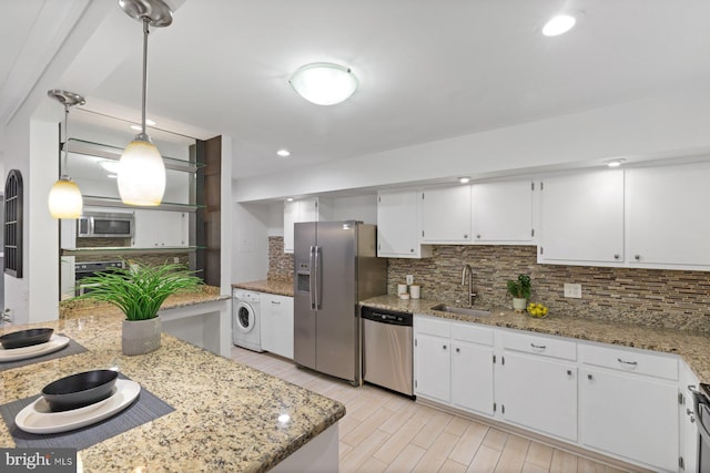 29 Stonehenge Cir Unit 6, Pikesville, MD 21208 - kitchen featuring washer / dryer, appliances with stainless steel finishes, a sink, decorative backsplash, and white cabinetry
