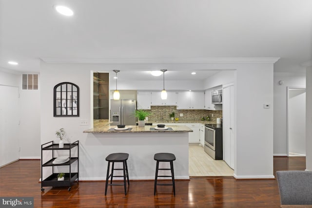 29 Stonehenge Cir Unit 6, Pikesville, MD 21208 - kitchen featuring appliances with stainless steel finishes, a peninsula, crown molding, tasteful backsplash, and recessed lighting