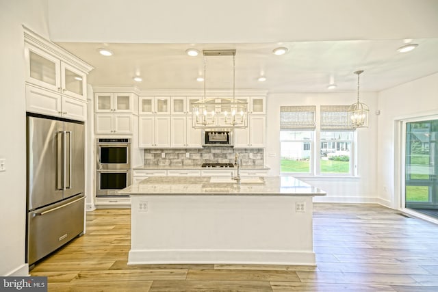 35024 Black Walnut Dr, Lewes, DE 19958 - kitchen with stainless steel appliances, a chandelier, white cabinets, tasteful backsplash, and light stone counters