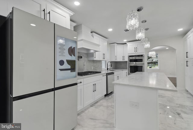 7746 16th St NW, Washington, DC 20012 - kitchen featuring appliances with stainless steel finishes, arched walkways, light marble finish flooring, a center island, and white cabinets
