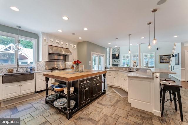5026 Huntwood Manor Dr, Fairfax, VA 22030 - kitchen featuring under cabinet range hood, a sink, butcher block counters, a spacious island, and recessed lighting