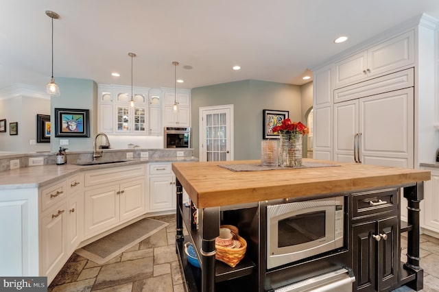 5026 Huntwood Manor Dr, Fairfax, VA 22030 - kitchen featuring appliances with stainless steel finishes, a sink, wooden counters, a center island, and white cabinetry