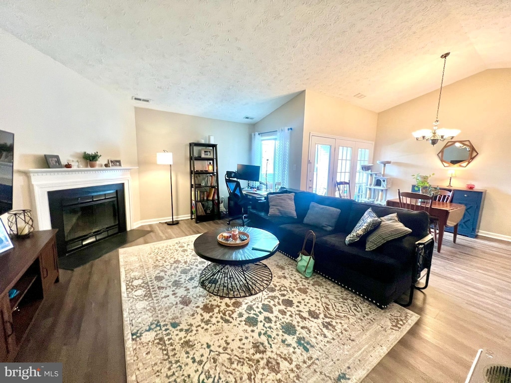 2125 Wainwright Ct Unit 2C, Frederick, MD 21702 - living area with vaulted ceiling, wood finished floors, a textured ceiling, a chandelier, and a fireplace with flush hearth