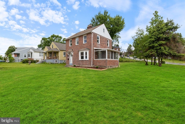 2318 Cloville Ave, Baltimore, MD 21214 - view of front of house featuring brick siding, a chimney, a front lawn, and a sunroom