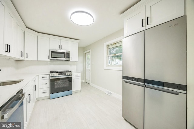 2831 Goucher Ave, Delanco, NJ 08075 - kitchen featuring appliances with stainless steel finishes, white cabinetry, light countertops, baseboards, and a sink
