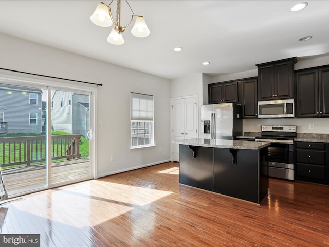 100 Norwood Dr, Falling Waters, WV 25419 - kitchen featuring appliances with stainless steel finishes, a kitchen island, a kitchen breakfast bar, a chandelier, and wood-type flooring