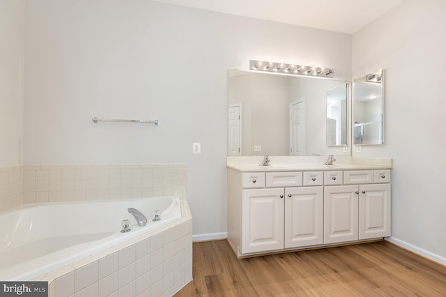 3839 Mulberry Point Ct, Dumfries, VA 22025 - bathroom featuring wood finished floors, double vanity, a bath, and baseboards