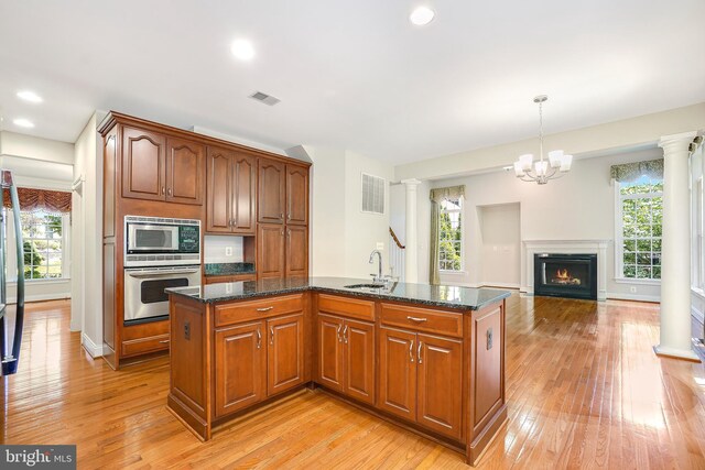 3530 Schuerman House Dr, Fairfax, VA 22031 - kitchen with stainless steel appliances, ornate columns, light wood finished floors, a sink, and dark stone countertops