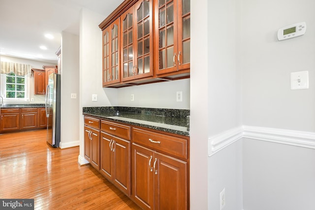 3530 Schuerman House Dr, Fairfax, VA 22031 - kitchen with freestanding refrigerator, light wood-style flooring, glass insert cabinets, and dark stone countertops