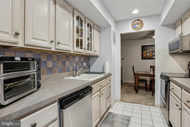 700 Avondale Rd Unit Ph-12, Wallingford, PA 19086 - kitchen with stainless steel appliances, a sink, light tile patterned floors, tasteful backsplash, and glass insert cabinets
