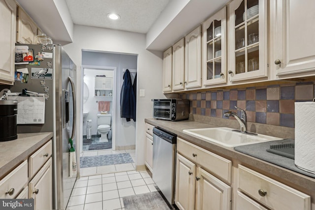 700 Avondale Rd Unit Ph-12, Wallingford, PA 19086 - kitchen featuring appliances with stainless steel finishes, a sink, light tile patterned flooring, decorative backsplash, and glass insert cabinets