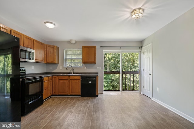 430 Cedar Creek Dr, Harpers Ferry, WV 25425 - kitchen with black appliances, a sink, light wood-style flooring, dark countertops, and brown cabinetry