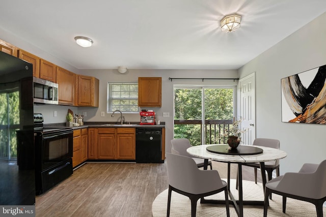 430 Cedar Creek Dr, Harpers Ferry, WV 25425 - kitchen with black appliances, a sink, light wood-style flooring, dark countertops, and brown cabinets