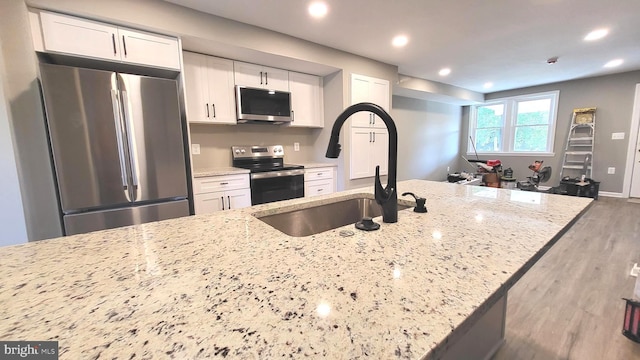 248 W Edgevale Rd, Baltimore, MD 21225 - kitchen with appliances with stainless steel finishes, white cabinetry, wood finished floors, light stone counters, and recessed lighting